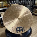 Kruhový činel z bronzu s viditelným rýhováním a nepravidelným povrchem. V dolní části je černý nápis MEINL a vedle něj stylizované logo znázornující…
