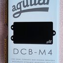 Fotografie znázorňuje černý snímač do basové kytary v originálním bílém obalu. Na obalu je nápis aguilar a modelové označení DCB-M4 spolu s popisem t…