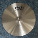 Kruhový mosazný činel s broušeným povrchem. Na povrchu je černý nápis „EXTRA THIN 18"“ a logo „Paiste Masters“. Činely vykazují mírné zaprášení.