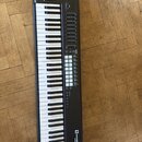 Černý MIDI kontrolér s klaviaturou, faderem a řadou posuvníků. V pravém dolním rohu je bílé logo novation a pod ním nápis Launchkey. Povrch přístroje…