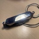 Na fotografii je elektrický snímač s chromovaným krytem oválného tvaru. K snímači vedou tři izolované vodiče v barvách černé, bílé a modré. Povrch ch…