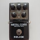 Černý kytarový efekt s nápisy METAL CORE a DELUXE MKII. V horní části jsou pět kontrolních knoflíků s popisky BASS, MIDDLE, TREBLE, GAIN a MASTER, př…