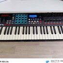 Černý MIDI kontrolér s klávesnicí. Na levé straně je nápis AKAI PROFESSIONAL a modelové označení MPK249. Přístroj obsahuje modrý podsvícený pad kontr…