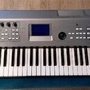 Stříbrný digitální klavír s bílými a černými klávesami. Na horní části je vlevo logo YAMAHA s doprovodným symbolem, vpravo nápis MM6 a vlevo nad kláv…