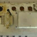 Zadní strana stříbrného elektronického zařízení s kovovým šasi. V horní části je osm kruhových konektorů, z nichž první tři jsou černé a zbývajících…