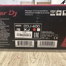 Fotografie zachycuje část kartonového obalu od DJ kontroléru. Na krabici je červené logo Pioneer DJ a nápis MODEL: DDJ-400. Jsou zde uvedeny technick…