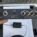 Zadní strana černého elektronického zařízení s nápisy LEXICON LXP-1, SERIAL NO. (za ním je nečitelný kód) a ASSEMBLED IN HONG KONG. Jsou zde vidět ko…