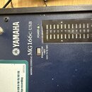 Detailní pohled na horní část modrého míchacího pultu. Na povrchu je bílý nápis YAMAHA s logem, označení MIXING CONSOLE MG166C-USB a svítící zelená k…