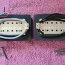 Dvě humbuckery s kovovými kryty v barvě stříbra, umístěné na černých pěnových podložkách. Na levém je nápis „ironGear HAMMER HEAD“ a „NECK POSITION“,…