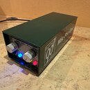 Tmavě zelený mikrofonní předzesilovač v kovovém šasi. Na předním panelu je nápis DAKING Mic-Pre One, dva stříbrné kovové ovraty a dvě svítící kontrol…
