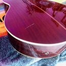 Detail zadní strany akustické kytary v tmavě červené barvě s viditnou strukturou dřeva. Povrch je lakovaný a glossy, v dolní části je vidět bílý lem.…