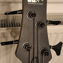Fotografie zachycuje hlavu basové kytary v matně černé barvě. Na horní části je bílé logo „SDGR“ a pod ním nápis „SOUNDGEAR BY IBANEZ“. Nástroj má čt…