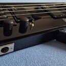 Detail korpusu černé elektrické basy s lesklým povrchem. Na korpusu jsou tři černé oválné potenciometry, přepínač a nápis „HORNER Professional BASS“.…