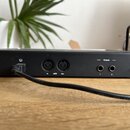 Zadní strana černého elektronického zařízení s několika konektory. Jsou zde dva MIDI porty s nápisy „In“, „MIDI“ a „Out“ a dva výstupy označené slove…