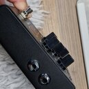 Černý efekt pedál s matným povrchem. Na boční straně jsou umístěny dva kovové konektory jack. Horní strana obsahuje tři černé oválné ovládací knoflík…