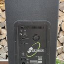 Zadní strana černého aktivního reproduktoru s texturovaným povrchem. Na zadním panelu je nápis kx12 FULL RANGE MODULE ACTIVE 500 WATT EXTREME RESOLUT…