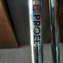 Detail chromovaného kovového trubkového nástroje. Na povrchu je nalepený štítek s černým nápisem PROEL® a menším svislým textem MADE IN ITALY. Nad ná…