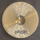 Kruhový činel zlaté barvy s viditelným rýhováním a kovaným povrchem. V dolní části je černé logo pAiste a nápis MADE IN SWITZERLAND. V centru činelu…