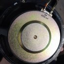 Fotografie zachycuje zadní část reproduktoru s kovovým magnetem stříbrné barvy. Na povrchu magnetu je černý nápis PP-8022 4Ω. K reproduktoru vedou dv…