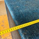 Detailní pohled na roh reproduktorové bedny potažené modrým texturovaným povrchem. Na hraně je přiložen žlutývstupní metr s viditelným rozmezím čísel…