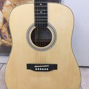 Akustická kytara s přírodním dřevěným povrchem korpusu a tmavým hmatníkem. Uvnitř ozvučnice je vidět štítek s nápisy „CUSTOM GUITARS“ a „quality“. Ná…