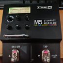 Černý efekt pedál s nápisy LINE 6 a M5 STOMPBOX MODELER. Pod názvem modelu jsou uvedeny kategorie DELAY | MOD | DISTORTION | FILTER | VERB. Displej z…