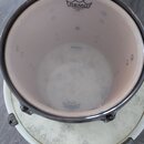 Pohled shora do vnitřku bubnu s dřevěným korpusem a kovovými obručemi. Na horní membráně je černé logo REMO a nápis AMBASSADOR. Na spodní membráně je…