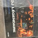 Fotografie zachycuje část černého DJ kontroléru, na kterém leží v plastovém obalu dokument s nápisy „DEVENEZ UN DJ LÉGENDAIRE“, „serato.com/FLX4“ a „…