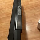 Fotografie zachycuje detail horní části černého plastového elektronického klávesu. Na povrchu je bílý nápis CASIO a nad ním text 210 SOUND TONE BANK.…