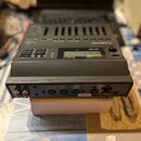 Černý zvukový modul s displejem a ovládacími tlačítky. Na přední straně je nápis Roland a označení modelu SC-88. Zadní panel obsahuje různé konektory…