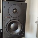 Černý studiový monitor s dvěma reproduktory. Na přední straně je nápis dynaudio acoustics. Nad hlavním reproduktorem je umístěn menší výšek s třemi o…
