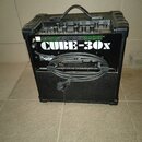 Černý kytarový kombozesilovač s úchytkou z plastu. Na přední straně je bílý nápis CUBE-30x a nad ním zelený grafický prvek. Před přístrojový panel s…