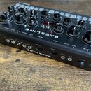 Černý syntezátor s nápisem BASSLINE a logem erica synths. Přístroj má řadu černých otočných ovladačů, několik přepínačů a bílé popisky funkcí. Na zad…
