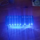 Modrý obdélníkový napájecí zdroj s nápisy CALINE POWER, ISOLATED PROTECTION a SCUNU. Na přední hraně svítí řada modrých LED diod. Do přístroje je v l…