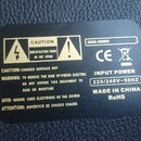 Fotografie zachycuje černý štítek s technickými informacemi a bezpečnostními varováními. Na štítku jsou nápisy CAUTION RISK OF ELECTRIC SHOCK DO NOT…