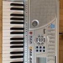 Stříbrný elektronický klávesový nástroj s bílými a černými klávesami. Na pravé straně je vidět mřížka reproduktoru a nápisy „Fox INSTRUMENTS“ a „128…