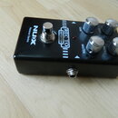 Černý kytarový efekt pedál s kovovými ovládacími knoflíky a stomečem. Na horní straně jsou nápisy NUX, Reissue Series, REC TO a DISTORTION. U knoflík…