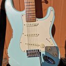Světle modrá elektrická kytara typu Stratocaster s bílým pickguardem a javorovým hmatníkem. Tělo vykazuje výrazné opotřebení lakového povrchu, zejmén…