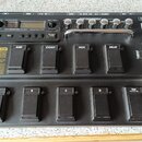Černý kytarový procesor s výrazným nápisem POD XT LIVE a logem LINE 6. Zařízení obsahuje řadu stomečů s popisky BANK $\triangle$, AMP, STOMP, MOD, DE…