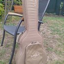 Hnědý polstrovaný obal na kytaru s úchytem a zipy. Na horní části je nápis GSmini, na přední kapse je logo Taylor obklopené nápisem QUALITY GUITARS.…