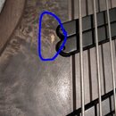 Detailní záběr na tělo basové kytary s tmavým dřevěným povrchem a dvěma černými snímači. Na povrchu těla je pod levým snímačem modrým kruhem vyznačen…