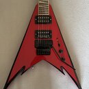 Červená elektrická kytara s ostrými hranami a černým lemováním. Na krku jsou dva humbuckery, z nichž na spodním je nápis Seymour Duncan. Nástroj má č…