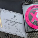 Fotografie zobrazuje příslušenství k hudebnímu nástroji. Je zde vidět certifikát s nápisy „FURCH“, „Certificate of Authenticity“, „Model: Bc 62-SW4 F…