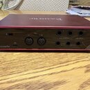 Zadní strana červeného audio rozhraní značky Focusrite. Jsou zde vidět konektory USB, dva MIDI porty s nápisy OUT a IN, čtyři LINE OUTPUTS a čtyři LI…