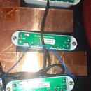 Tři elektrické snímače typu single-coil v bílých plastových rámečkách, umístěné na černé pickguardu s měděným stíněním. Horní snímač má zelený kryt s…