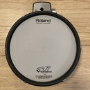 Elektronický buben bílé barvy s černým gumovým okrajem. Na membráně je nápis Roland, pod ním text MESH HEAD™ made by REMO a ve spodní části logo V-Dr…