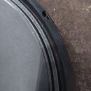 Detailní pohled na okraj černého bicího bubnu s napnutou černou membránou. Na černém kovovém obruči jsou vidět známky opotřebení v podobě hnědých rez…