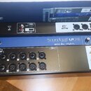 Černý digitální mixážní pult v rackovém provedení s modrým pruhem uprostřed. Na přístroji jsou nápisy Soundcraft Ui 16, lexicon, dbx a DiGiTech. Zaří…