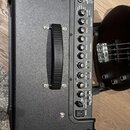 Černý kytarový kombozesilovač s texturovaným povrchem a plastovou rukojetí, na které je nápis BOSS. Ovládací panel obsahuje logo KATANA a řadu potenc…