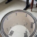 Fotografie znázorňuje buben s průhledným koženem. Na povrchu je vidět nápis EVANS a pod ním označení EC2S. Okraj koženu je zdoben černobílým vzorem a…